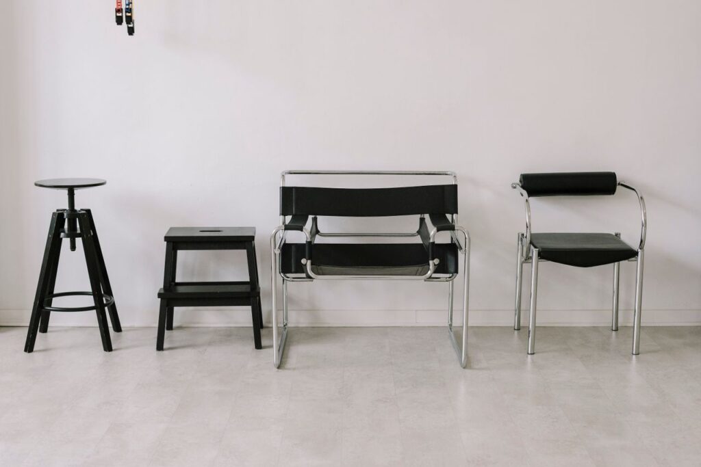 pexels-photo-30650069 A set of four black chairs in a minimalist indoor setting with a white wall background.